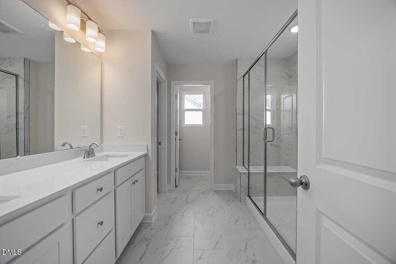 Modern master bath with white quartz double vanity, tiled floors, and glass shower in Davidson Homes The Gavin C, Lillington, NC