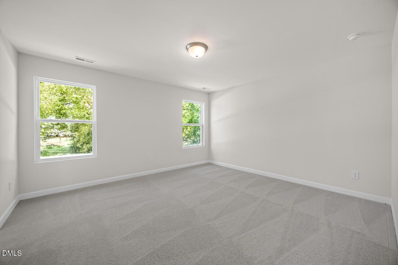 Spacious, carpeted bedroom with neutral walls and natural light in The Gavin A floor plan at Gregory Village, Lillington, NC.