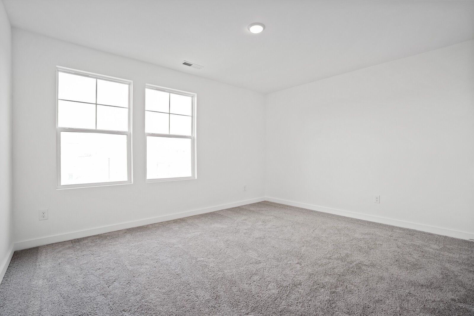 Bright empty bedroom with white walls, double windows, gray carpet in Davidson Homes The Logan C, Calista Farms, White House, TN