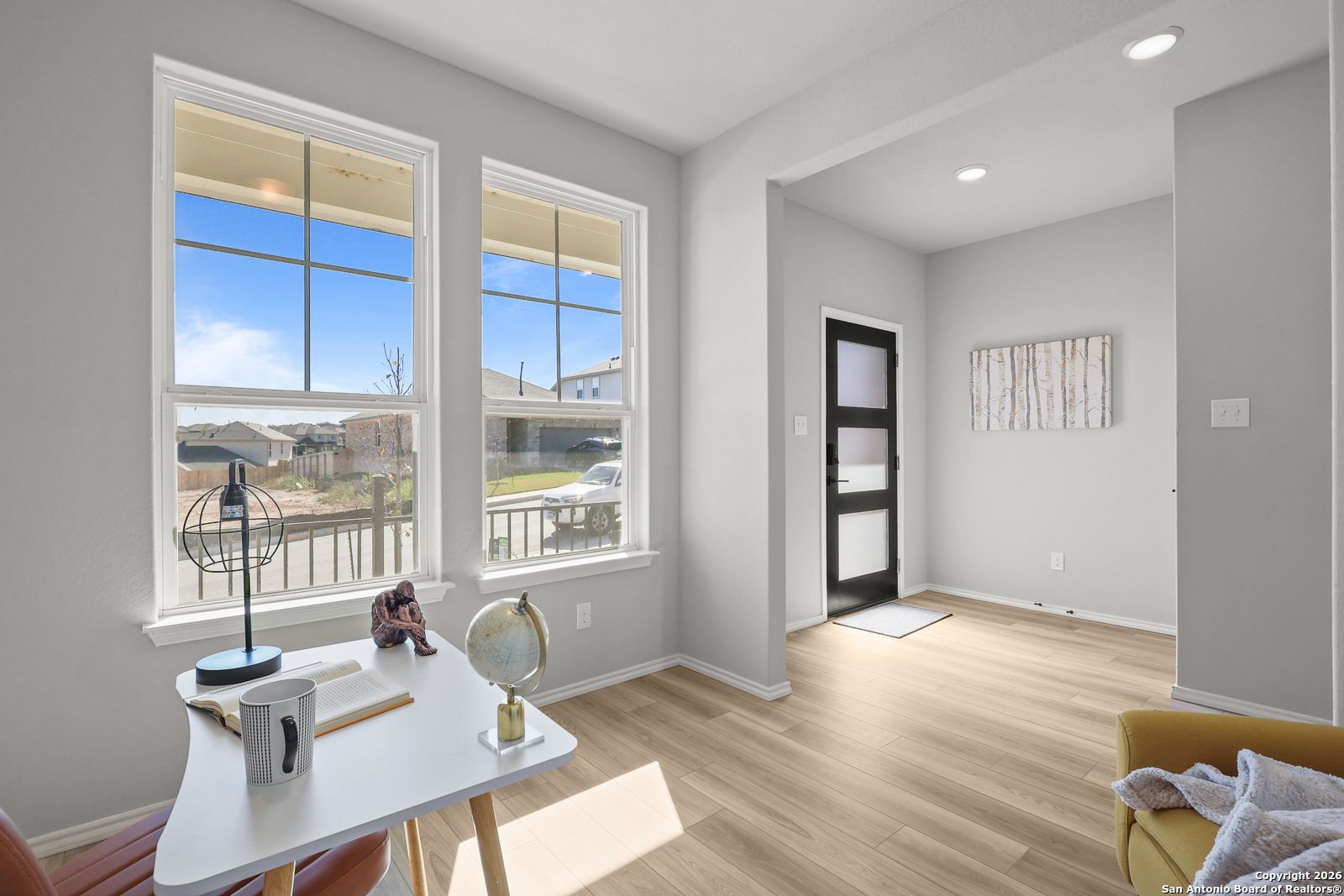 Bright home office with large windows, wooden desk, globe, and armchair in Davidson Homes The Murray K, San Antonio