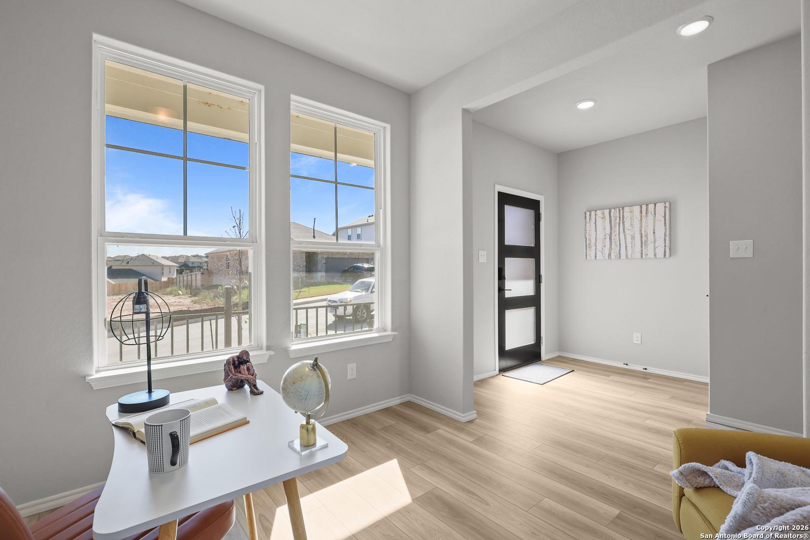 Bright home office with large windows, wooden desk, globe, and armchair in Davidson Homes The Murray K, San Antonio