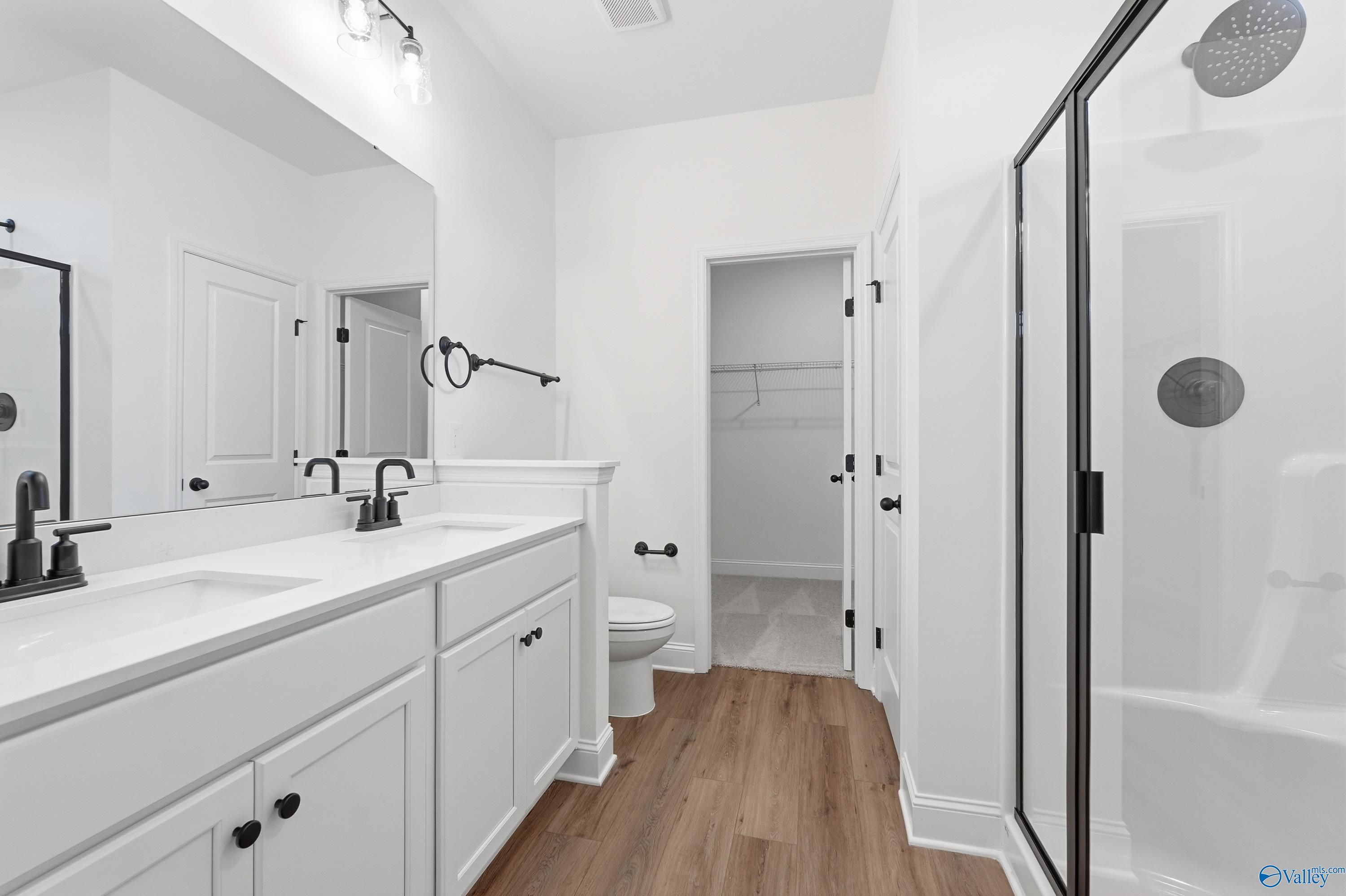 Modern primary bathroom with double vanity, walk-in shower, and closet in The Asheville C floor plan at The Highlands, Arab.