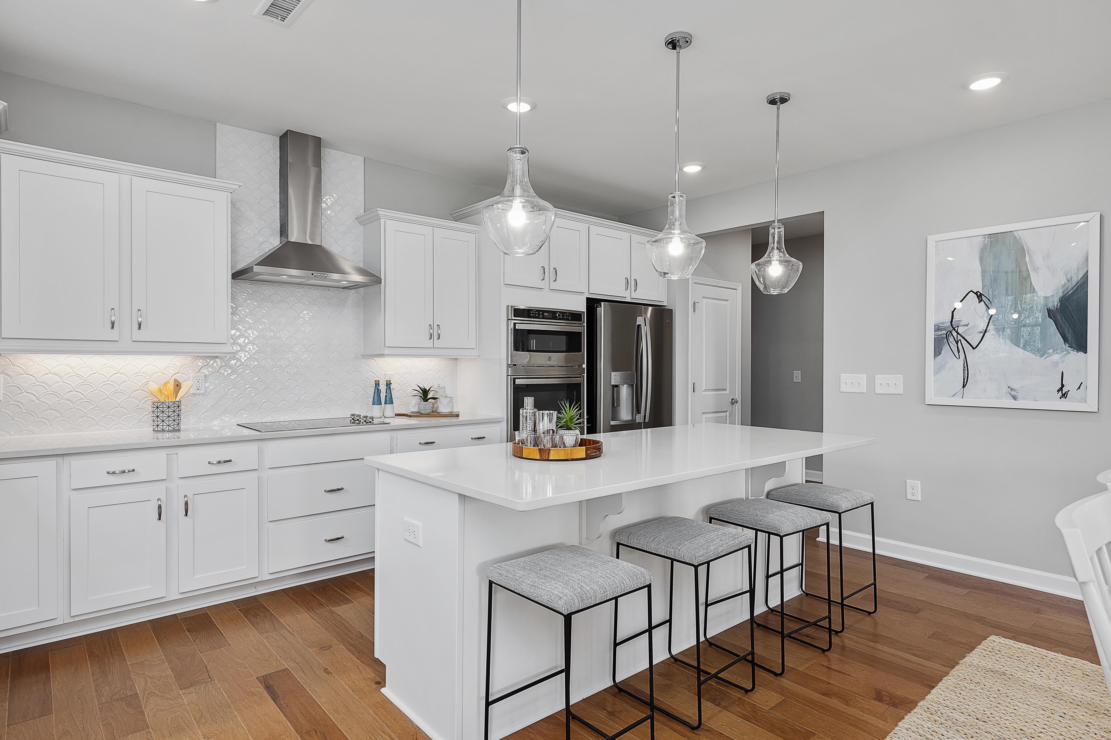 Spacious white kitchen with island, bar stools, stainless appliances, subway tile backsplash at Woodland Crossing in Zebulon NC