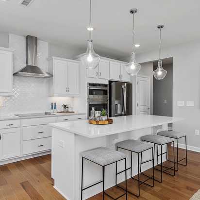 Modern white kitchen with island bar seating in Ashland, Apex NC by Davidson Homes, subway tile backsplash, hardwood floors