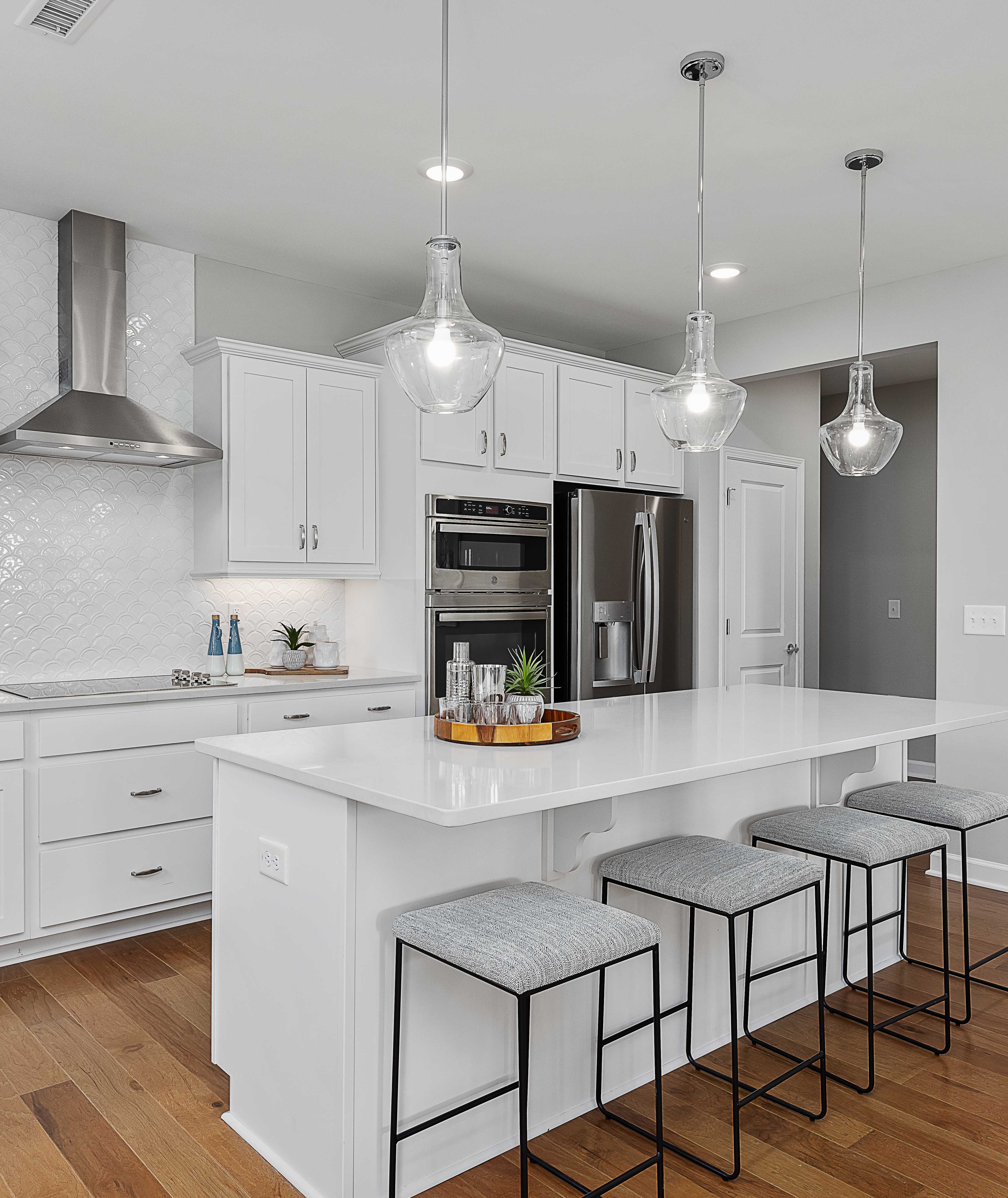 Modern white kitchen with island bar seating in Ashland, Apex NC by Davidson Homes, subway tile backsplash, hardwood floors