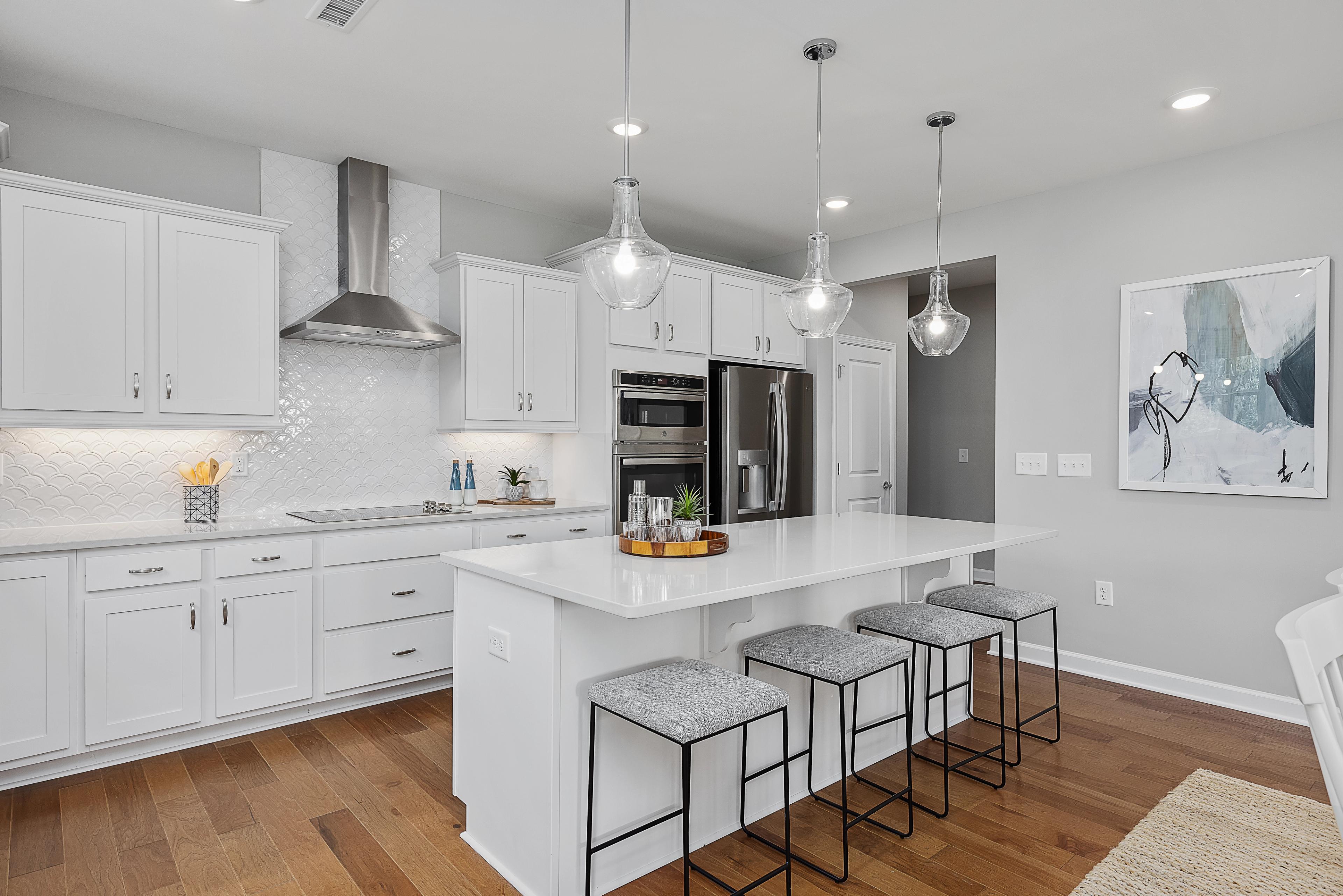 Modern white kitchen with island bar seating in Ashland, Apex NC by Davidson Homes, subway tile backsplash, hardwood floors