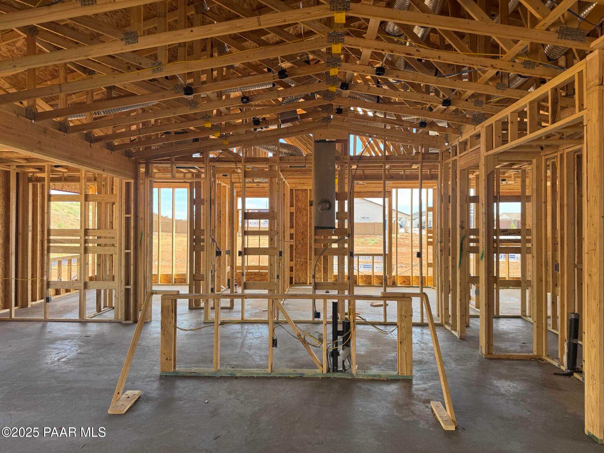 Open wooden framing of spacious great room with large windows and exposed beams in The Monarch B, Prescott Valley, Arizona