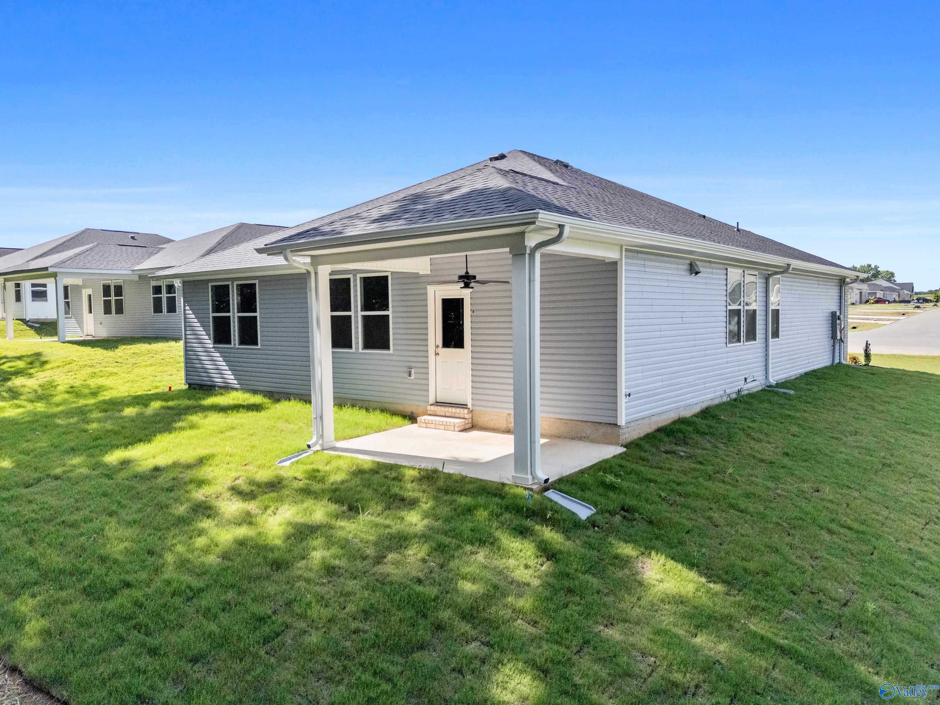 Modern single-story home exterior with covered porch, ceiling fan, white siding, and lush green lawn in Davidson Homes The Polaris, Bailey Park, Fayetteville, Tennessee