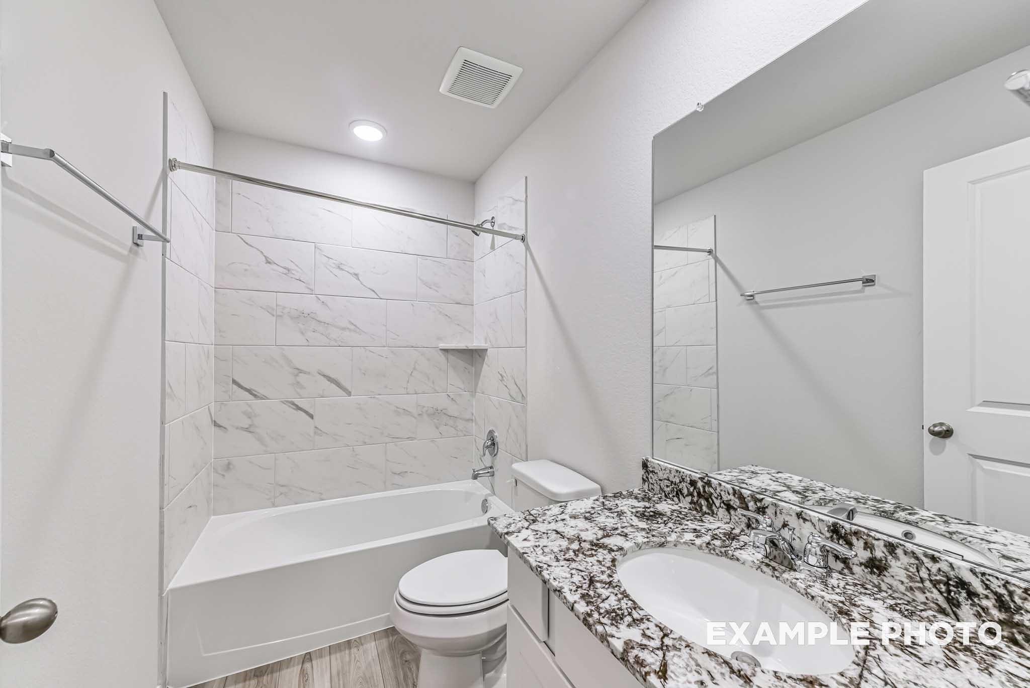 Modern guest bathroom with white subway tile shower, soaking tub, quartz vanity, and dual mirrors in Davidson Homes The Riviera A, Rosharon, Texas