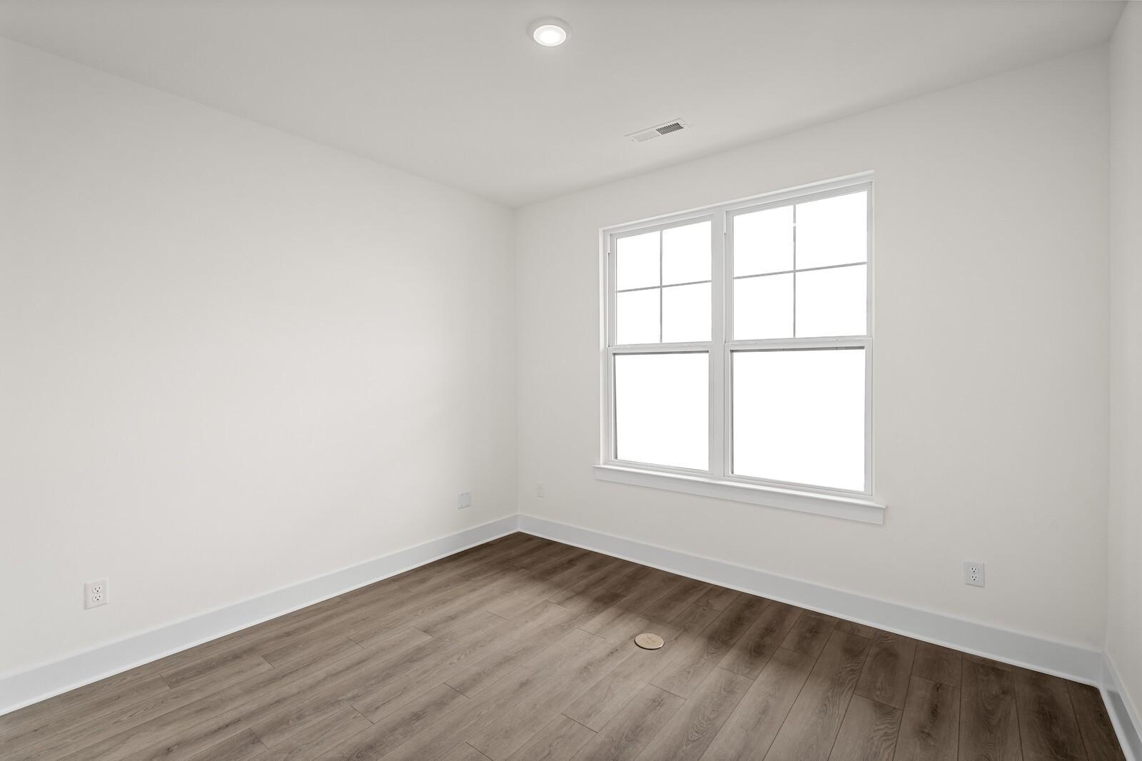 Bright, neutral bedroom with wood-style flooring in The Ridgeport D floor plan by Davidson Homes in Mt. Juliet, Tennessee.
