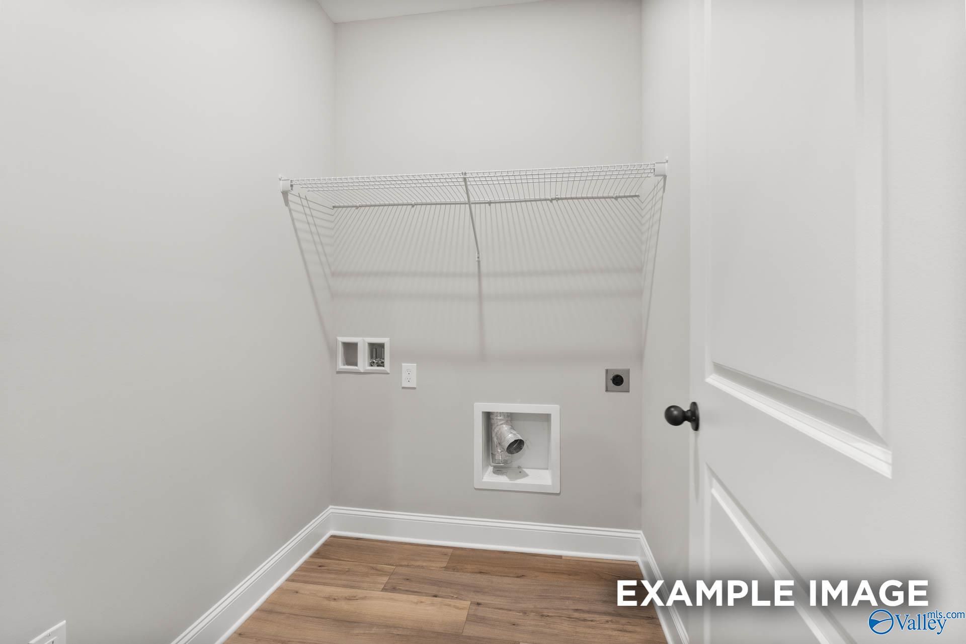 Spacious laundry room with wire shelving, washer/dryer hookups and hardwood floors in The Asheville C by Davidson Homes, Hazel Green, AL