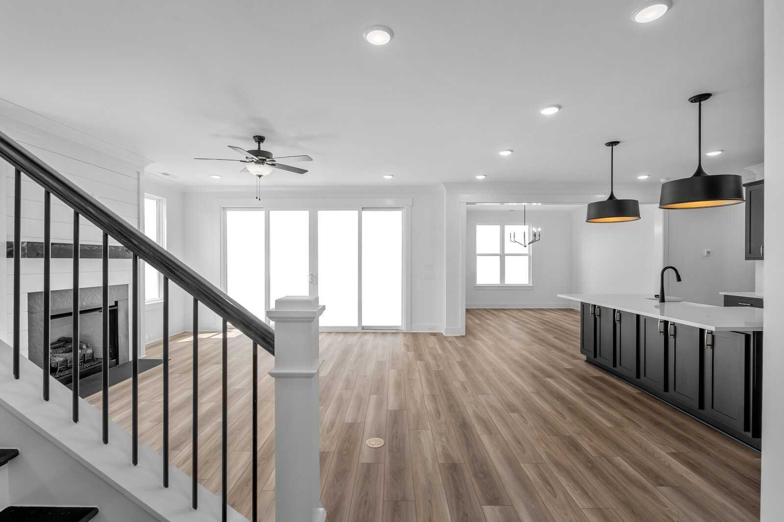 Open-concept great room featuring fireplace, wrought-iron staircase, and sleek kitchen island in Davidson Homes The Hathaway, Murfreesboro, TN