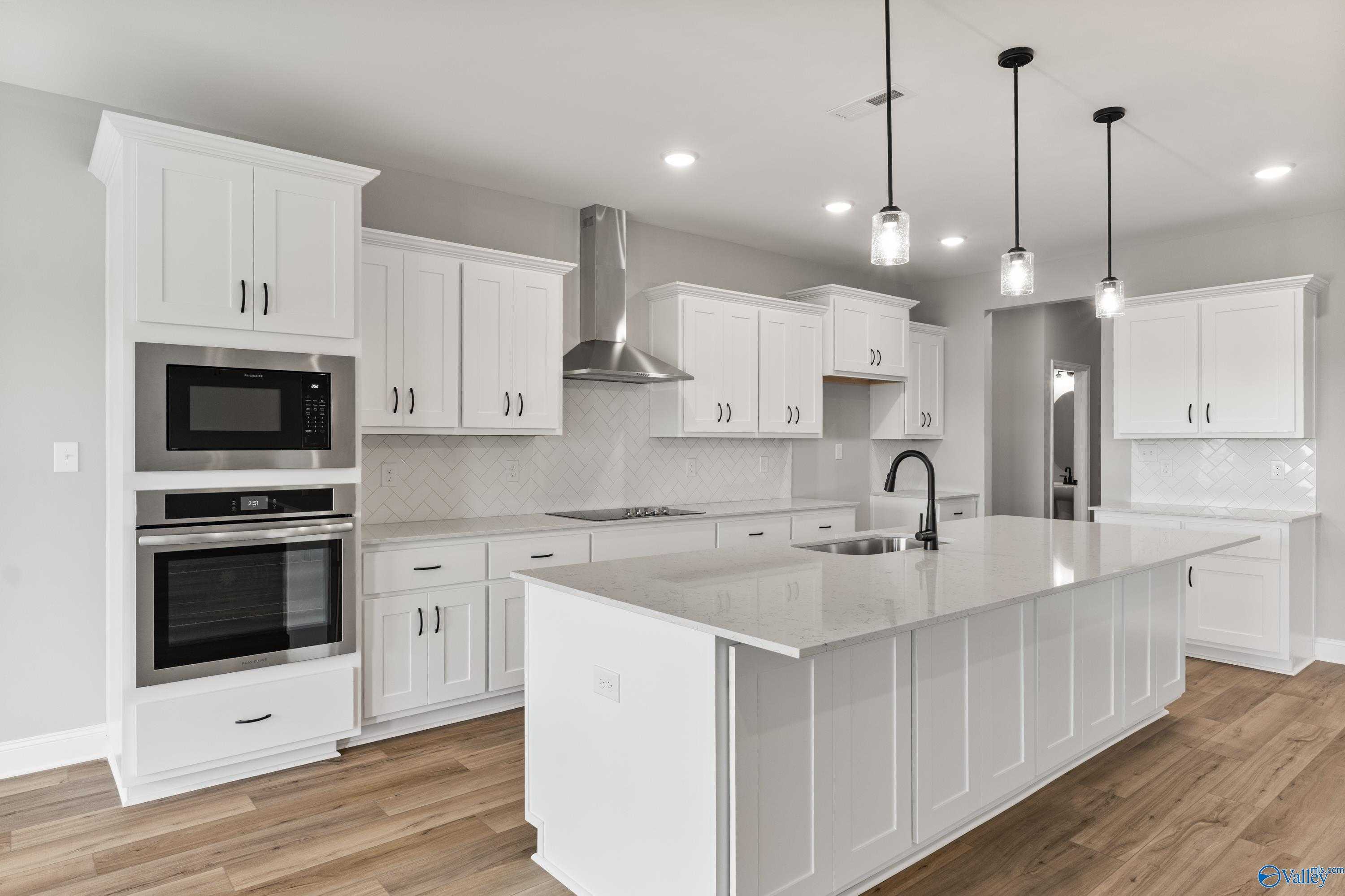 Modern white kitchen with quartz island, stainless double oven, subway backsplash in The Finleigh by Davidson Homes, Toney, AL