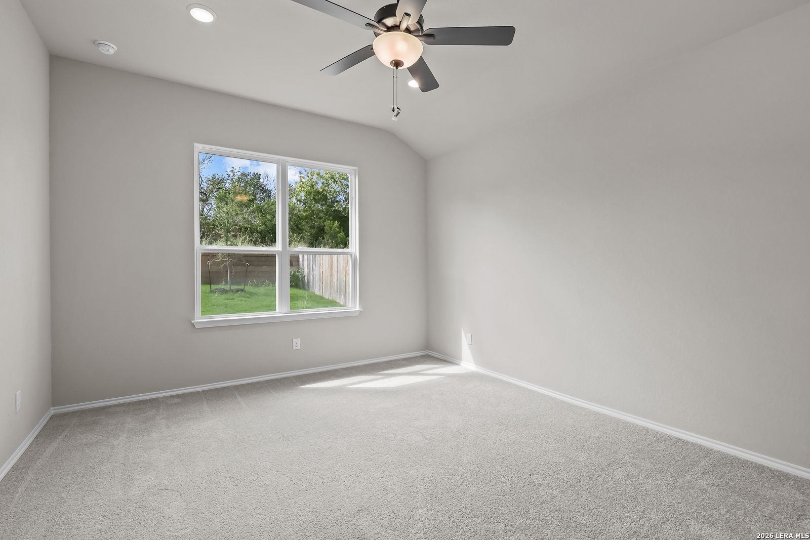 Bright bedroom with vaulted ceiling, ceiling fan, and backyard window in Davidson Homes The Sequoia C, Royal Crest, San Antonio