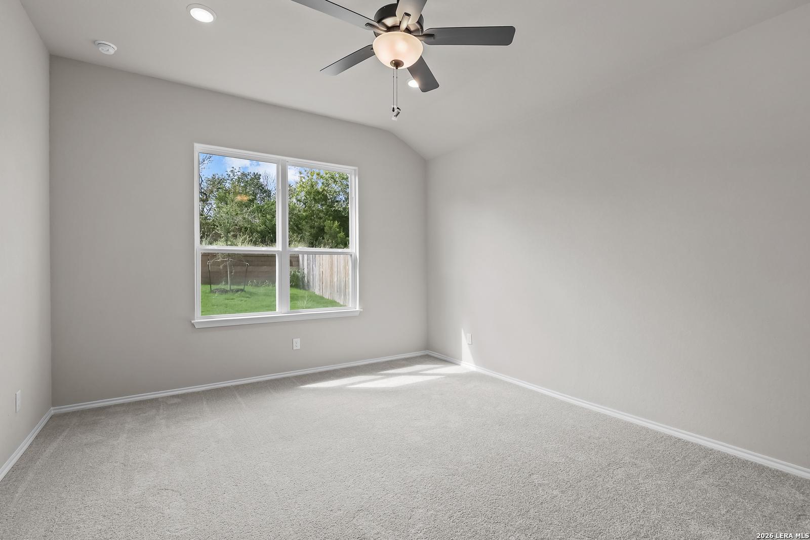 Bright bedroom with vaulted ceiling, ceiling fan, and backyard window in Davidson Homes The Sequoia C, Royal Crest, San Antonio