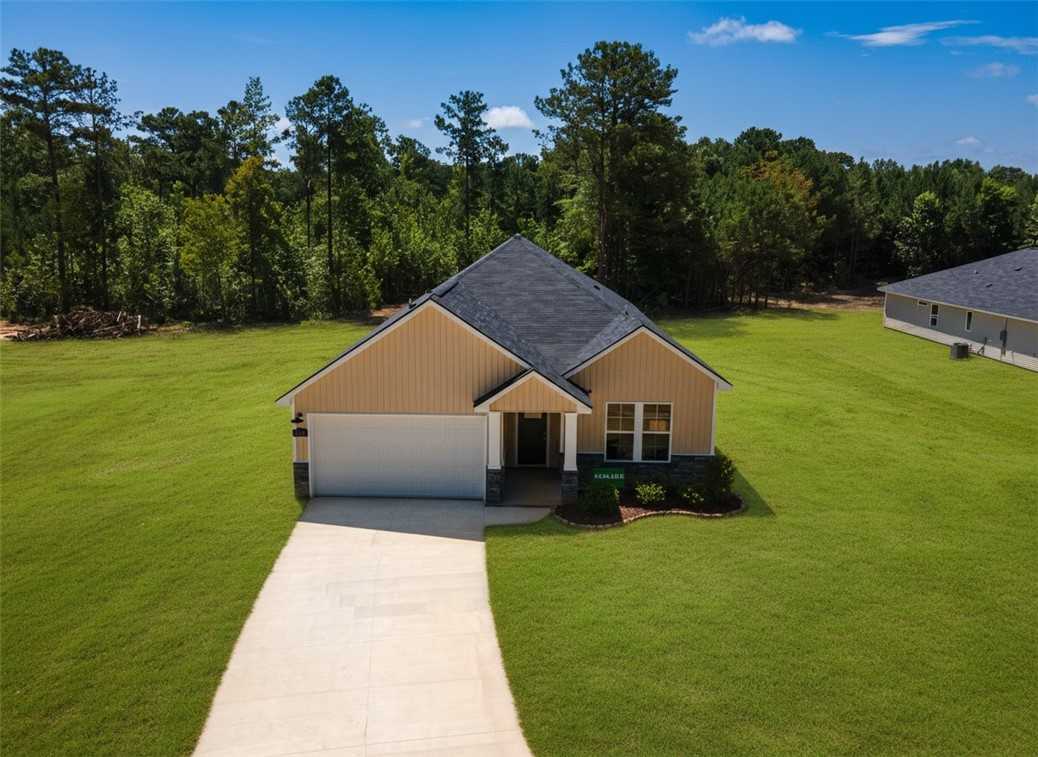 Modern one-story 4-bedroom home with beige siding, dark roof, one-car garage, and front porch in Silver Oak, Cusseta, Alabama