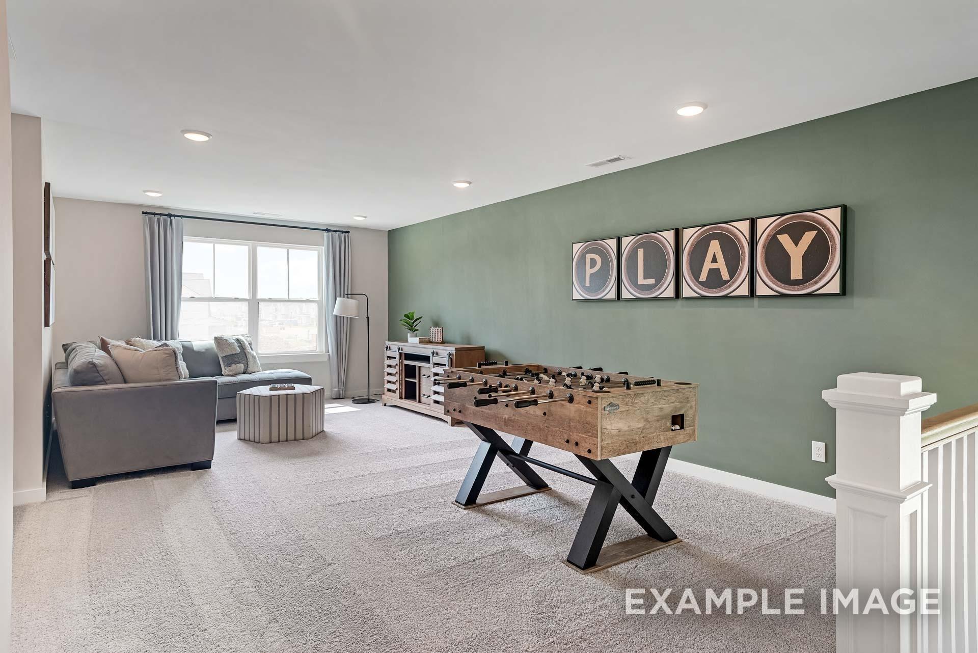 Upstairs game room with rustic foosball table, gray sofa, and green accent wall featuring "PLAY" sign in Davidson Homes The Ridgeport C, Gallatin, TN