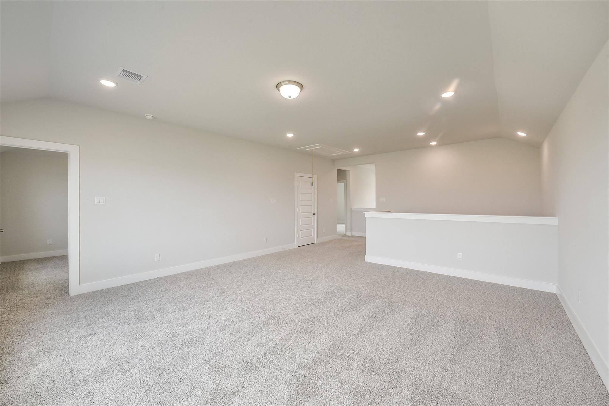 Spacious upstairs loft with neutral walls, plush carpet, and open balcony railing in 4-bedroom Davidson Homes The Philip B, Rosharon Texas