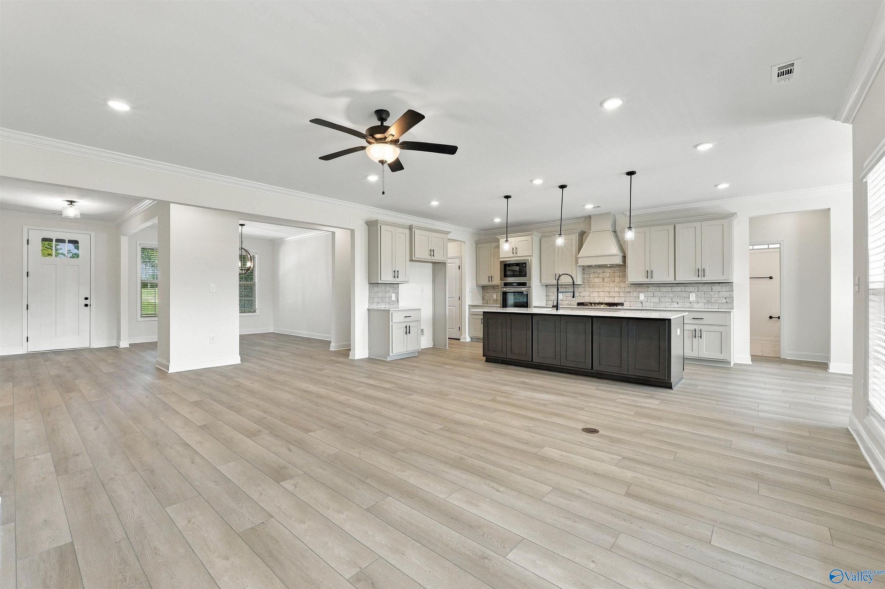 Open-concept kitchen with dark island, white cabinets, and luxury vinyl plank flooring in Davidson Homes Valencia floor plan, Huntsville