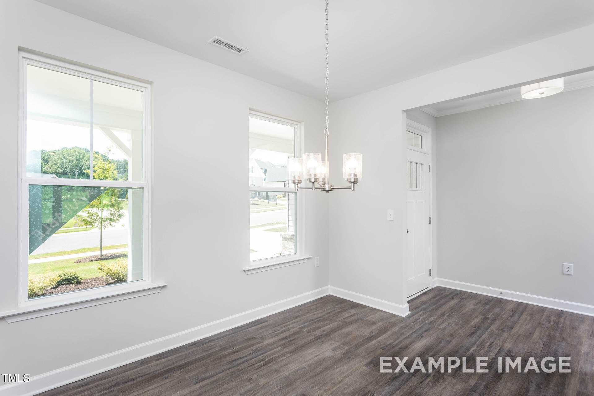 Bright dining room with hardwood floors, chandelier, and large windows overlooking green yard in The Willow B, Lillington, NC