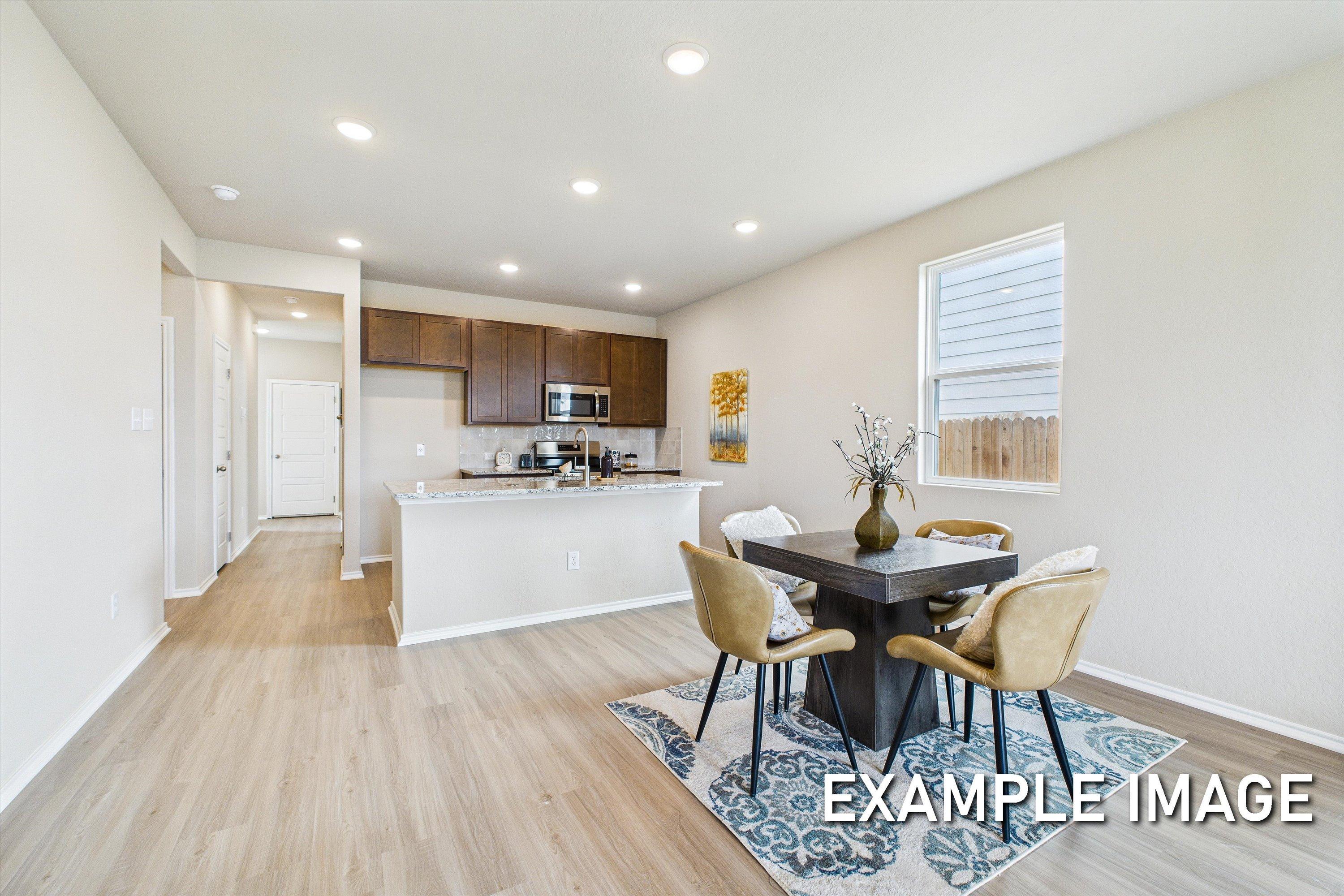 Open-concept kitchen and dining area in The Comal by Davidson Homes, featuring wood cabinetry and modern finishes.