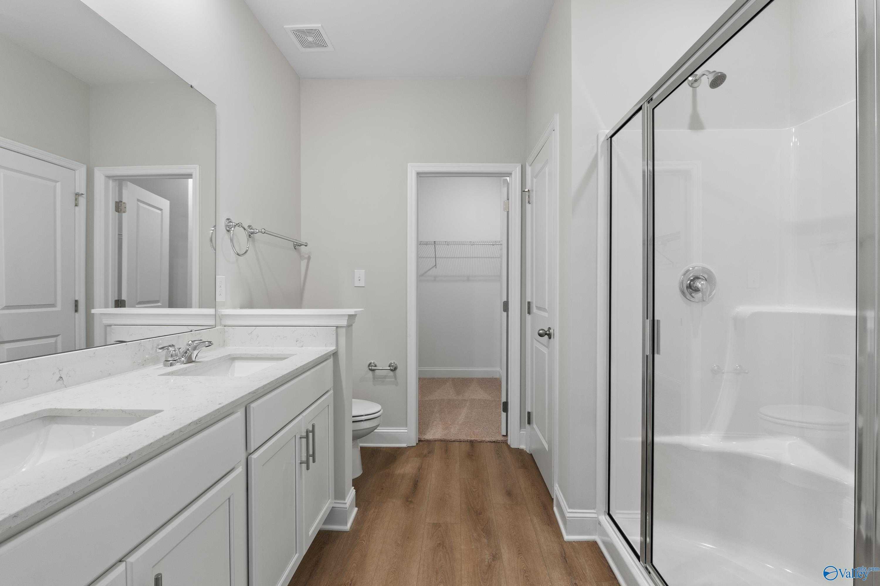 Modern master bathroom with double vanity, frameless glass shower, and walk-in closet in Davidson Homes The Asheville C, Huntsville AL