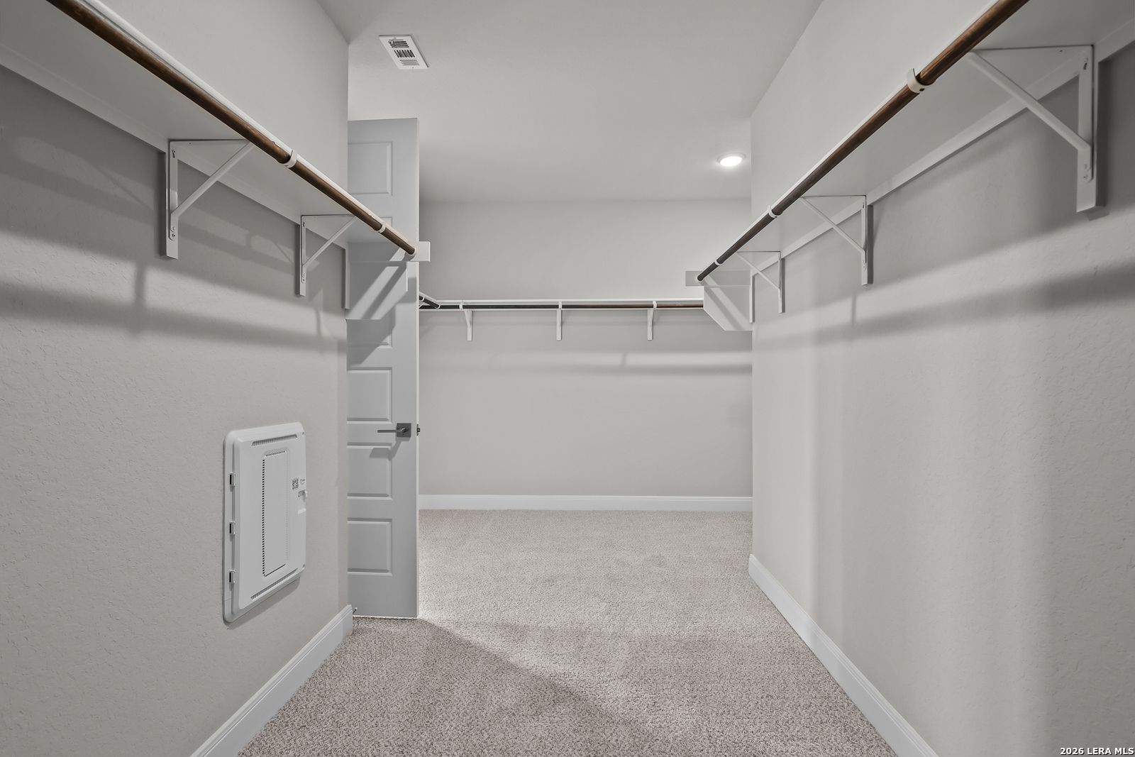 Spacious walk-in closet with wooden shelves and hanging rods in Davidson Homes The Rockford G, Ladera, San Antonio, Texas
