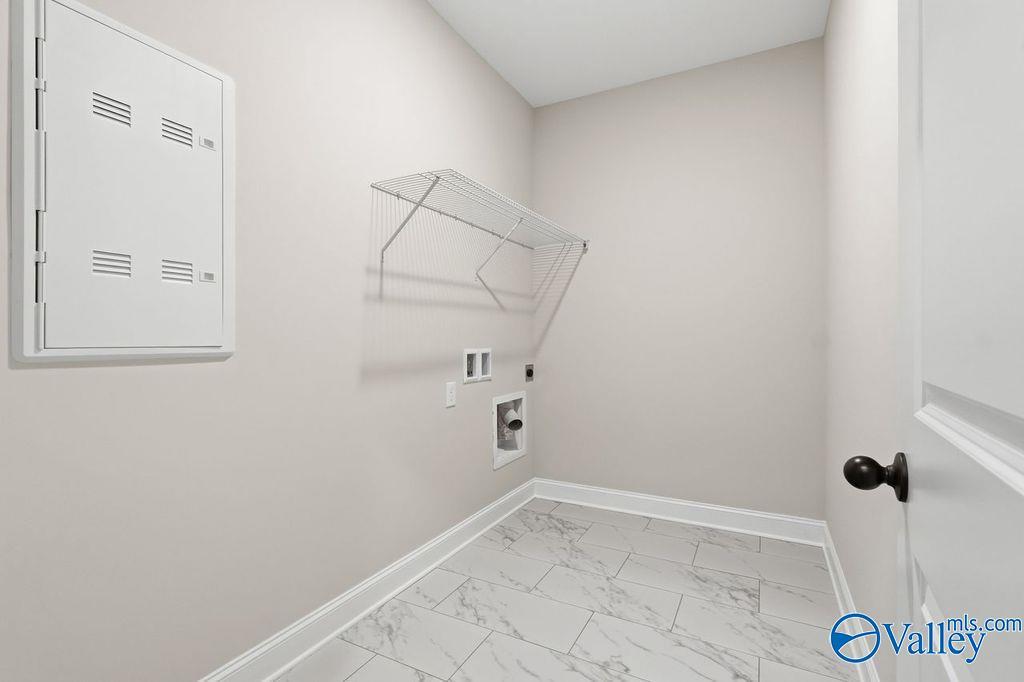 Spacious laundry room with built-in cabinet, glass shelf, washer/dryer hookups, and porcelain tile floor in Davidson Homes The Rockford B, Hartselle, Alabama