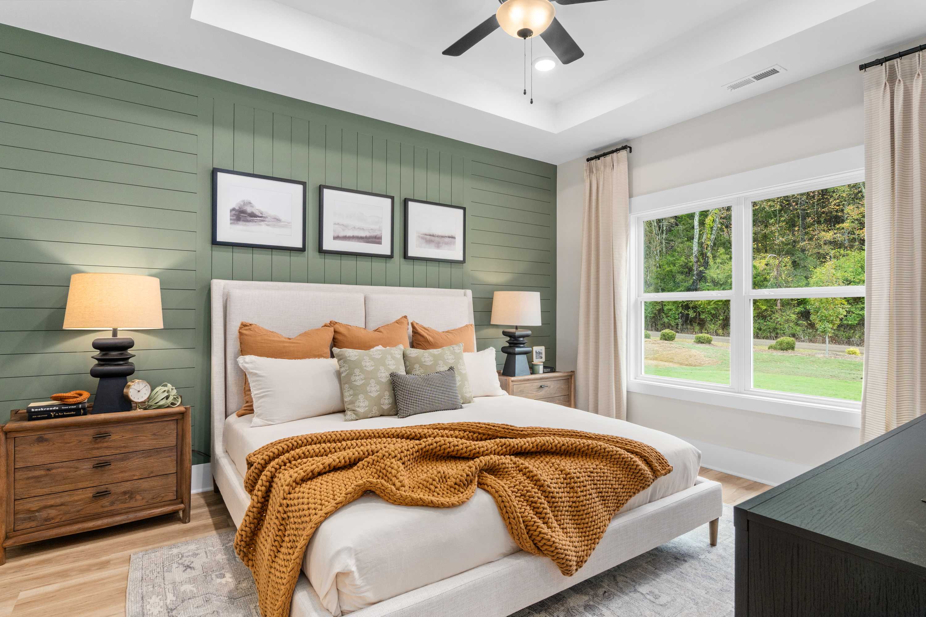 Spacious primary bedroom at Spragins Cove in Huntsville Alabama with green shiplap wall, king bed, and large window views