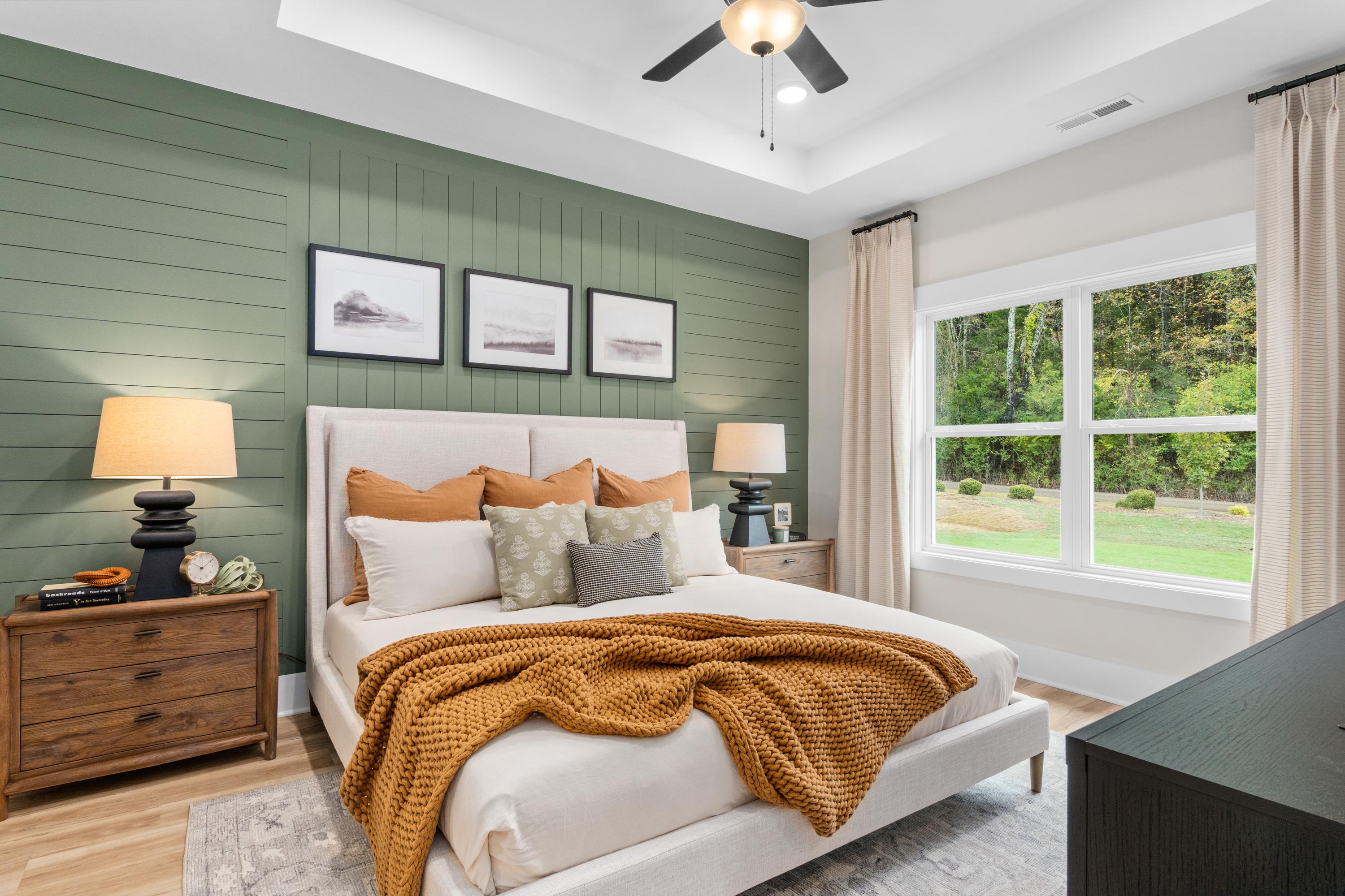 Spacious primary bedroom at Spragins Cove in Huntsville Alabama with green shiplap wall, king bed, and large window views