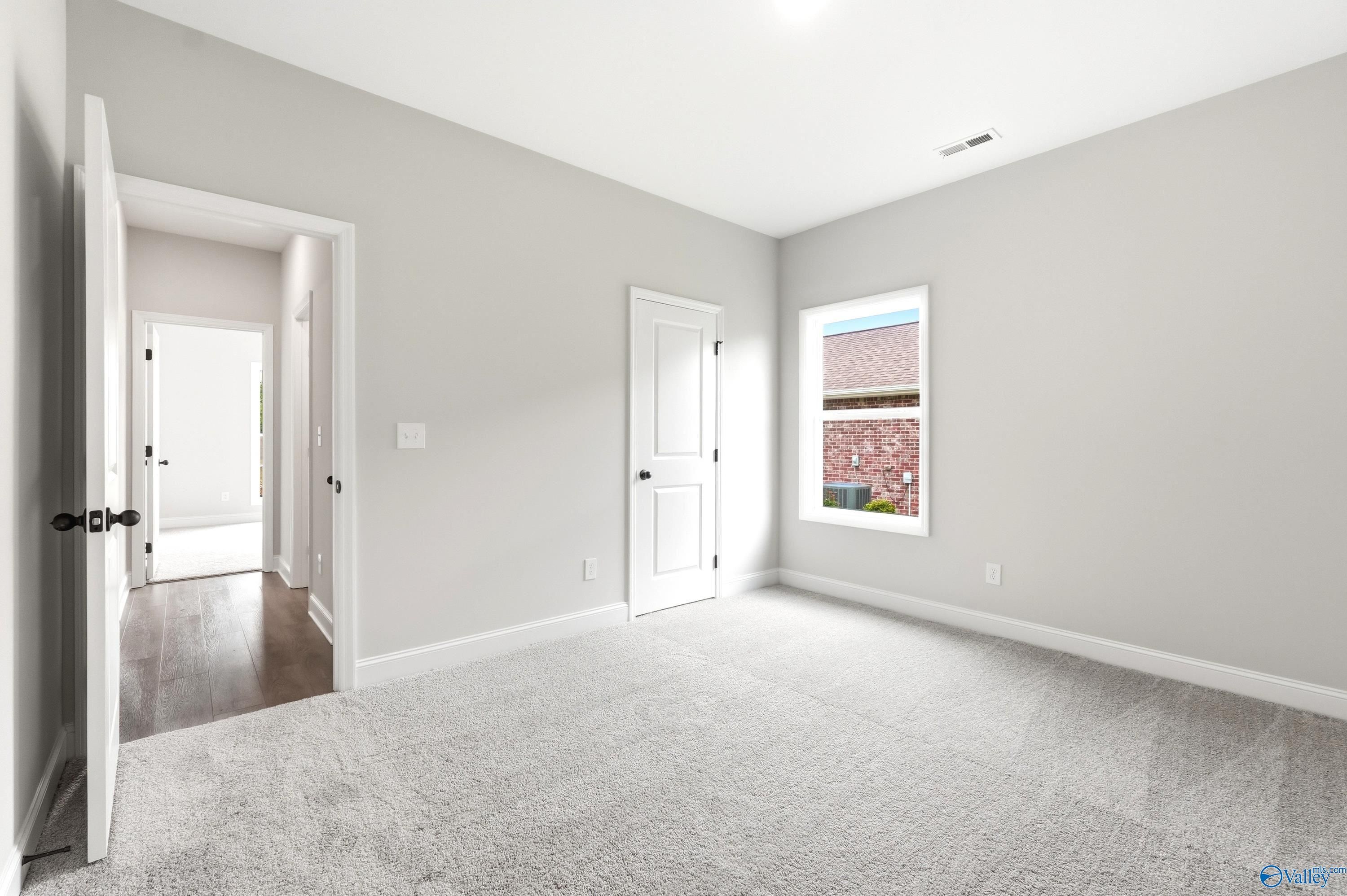 Bright, carpeted spare bedroom with neutral walls in The Daphne C floor plan at Flint Meadows, New Market, Alabama.