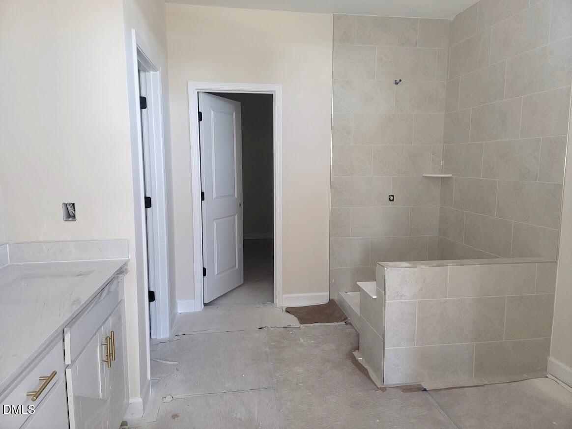 Spacious master bath with tiled walk-in shower, double vanity, and open door in Davidson Homes The Cypress B II, Angier, NC