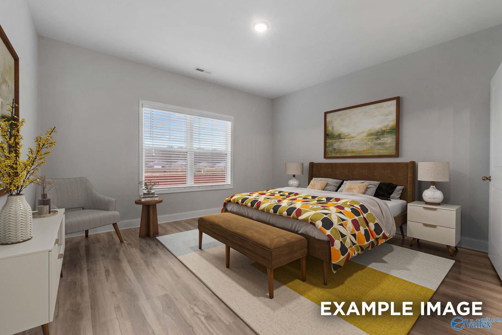 Cozy secondary bedroom with colorful king bed, gray walls, armchair, and wood floors in Davidson Homes The Cumberland B, Decatur, Alabama