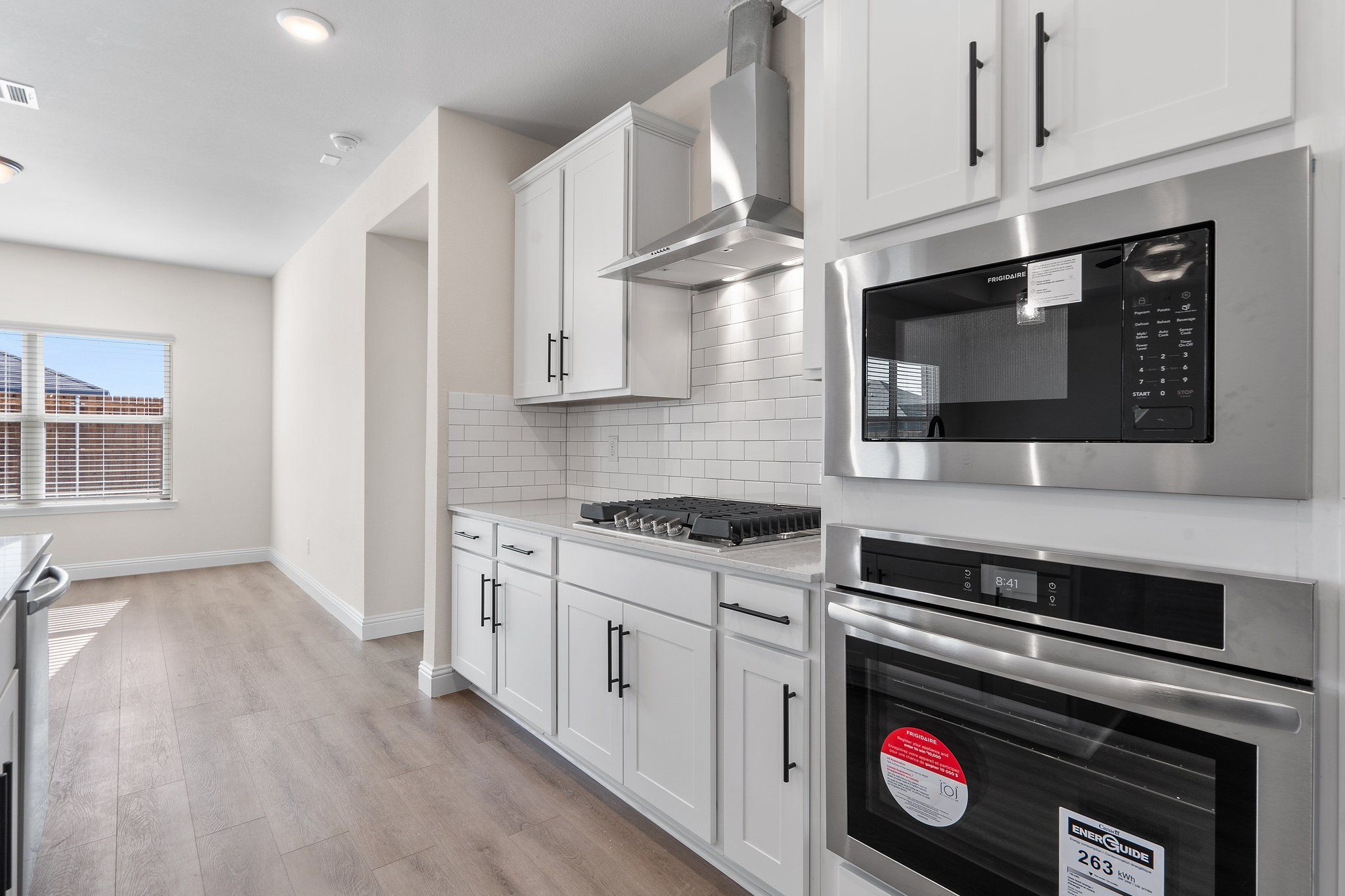 Modern kitchen in The Holly F home design featuring white cabinetry, subway tile backsplash, and stainless appliances.