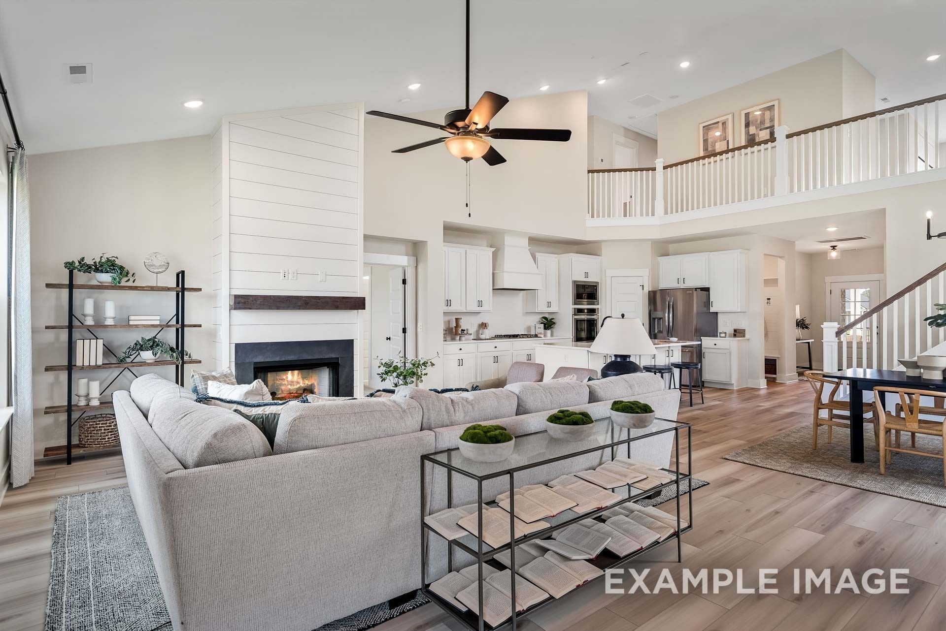 Open-concept living room with shiplap fireplace, gray sectional sofa, and modern kitchen in Davidson Homes The Ridgeport, Gallatin, TN