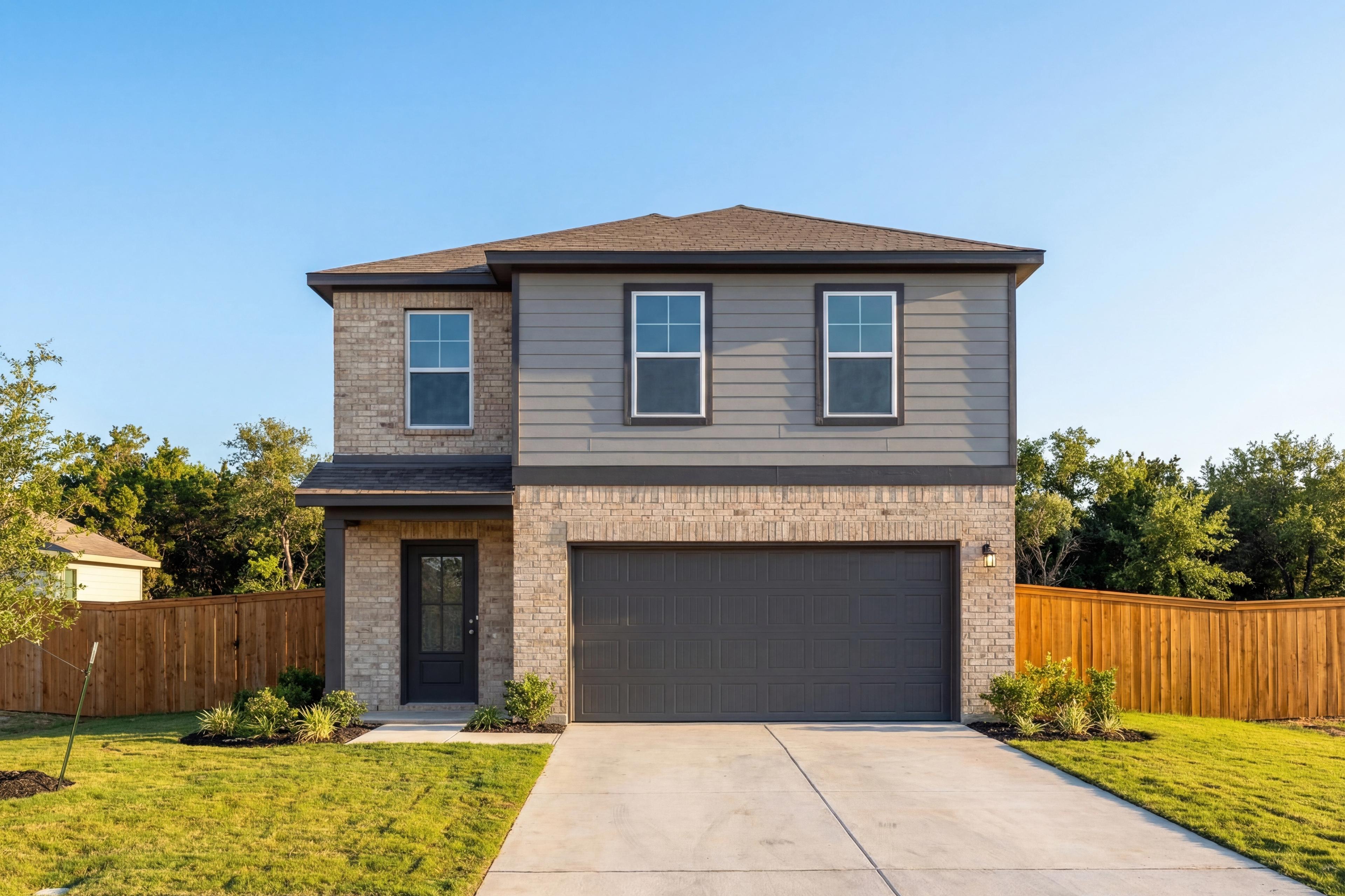 Modern two-story Brazos D home elevation with brick base, gray siding, two-car garage, and lush landscaping in San Antonio