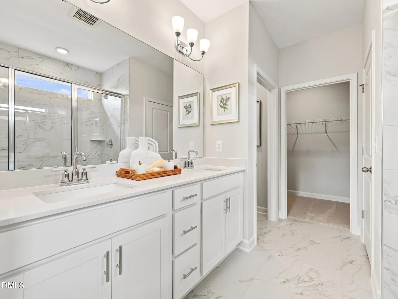 Modern master bathroom with dual vanity, marble-look tile, and walk-in closet in Davidson Homes The Daphne C, Zebulon, NC.
