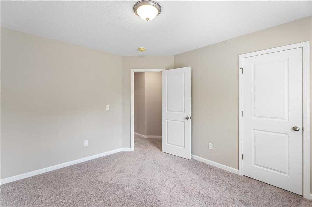 Empty bedroom with neutral beige walls, carpeted floor, and open door in Davidson Homes The Bartlett, Phenix City, Alabama