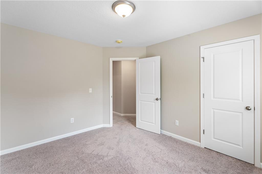 Empty bedroom with neutral beige walls, carpeted floor, and open door in Davidson Homes The Bartlett, Phenix City, Alabama