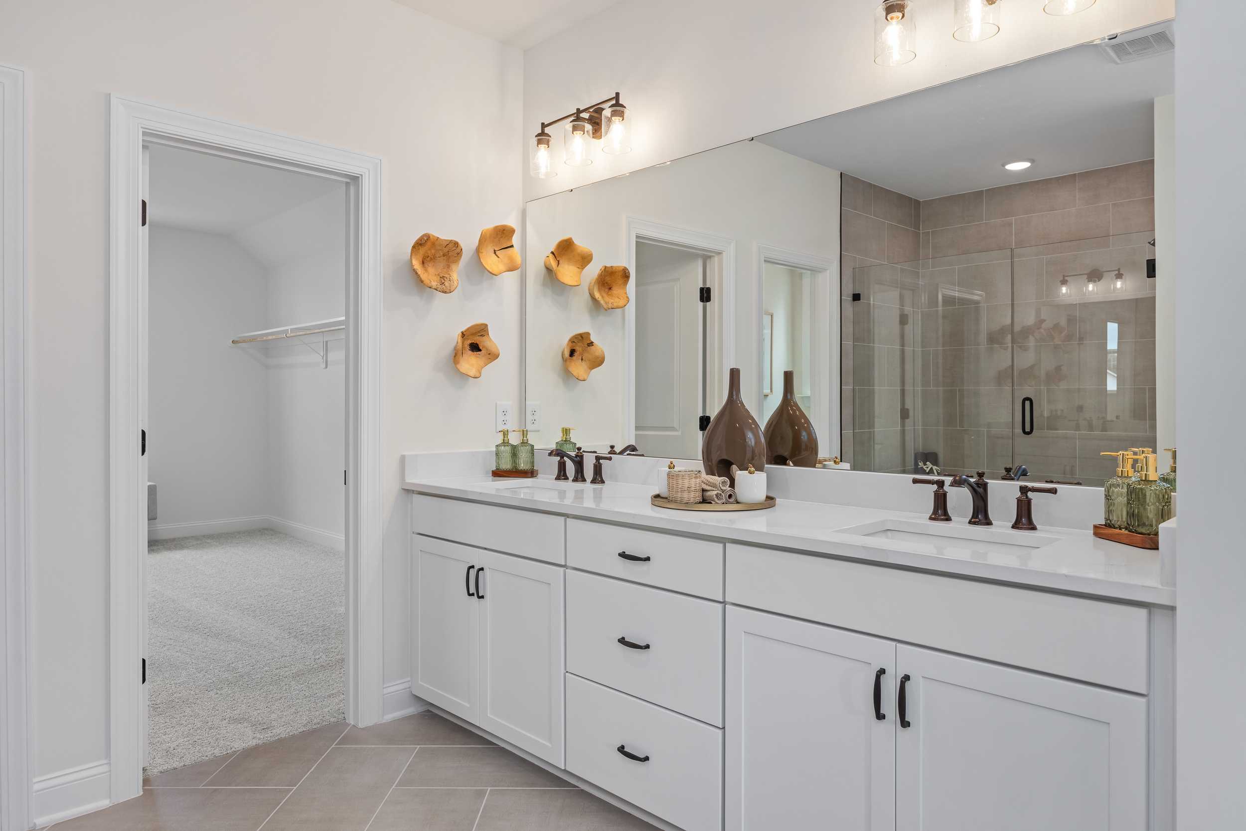 Spacious master bathroom at Laneridge Estates in Raleigh NC with white double vanity, frameless glass shower, and walk-in closet
