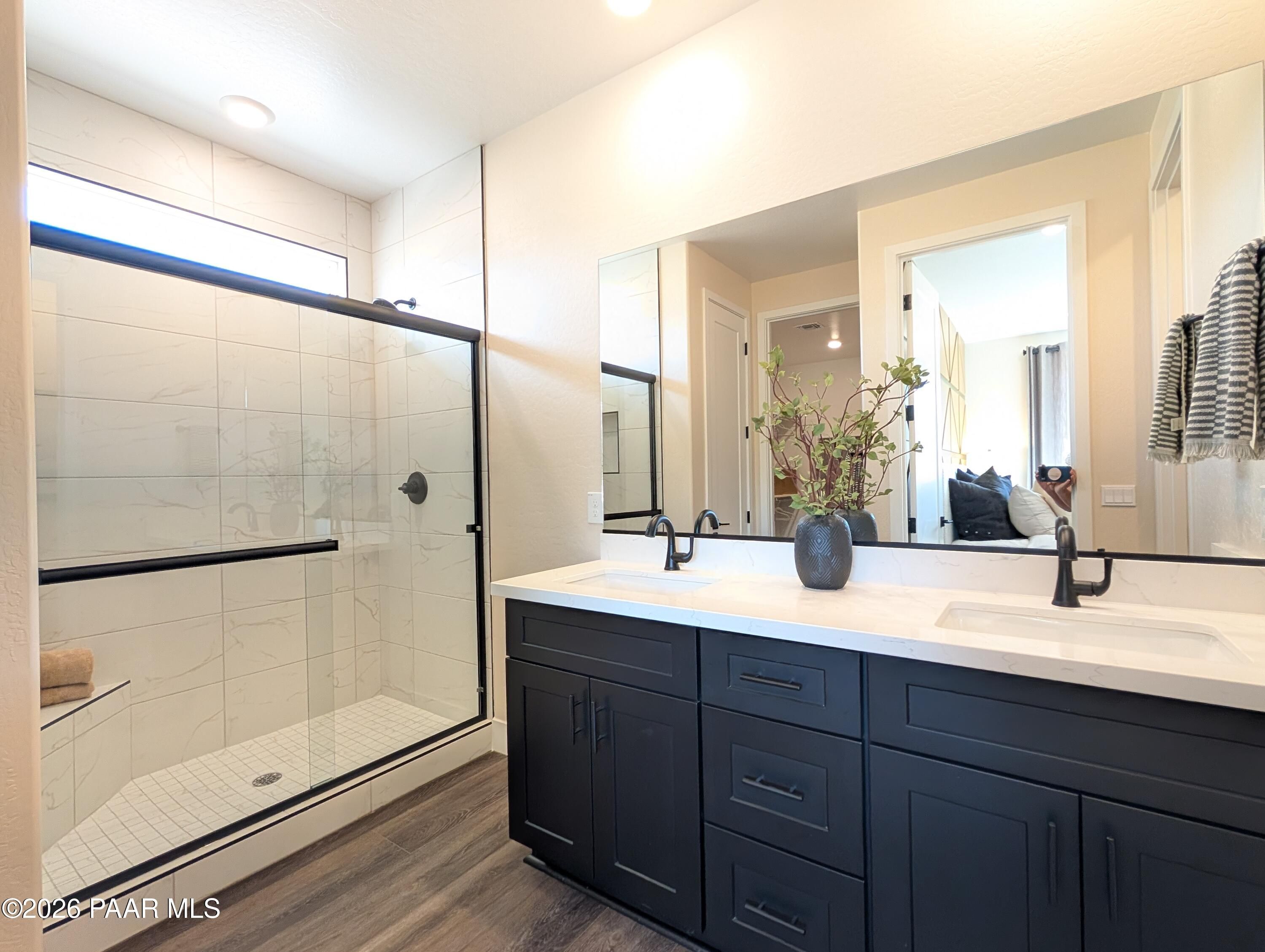 Modern bathroom with dual vanity, black cabinets, and walk-in shower in The Boulder II H at South Ranch, Prescott, Arizona.