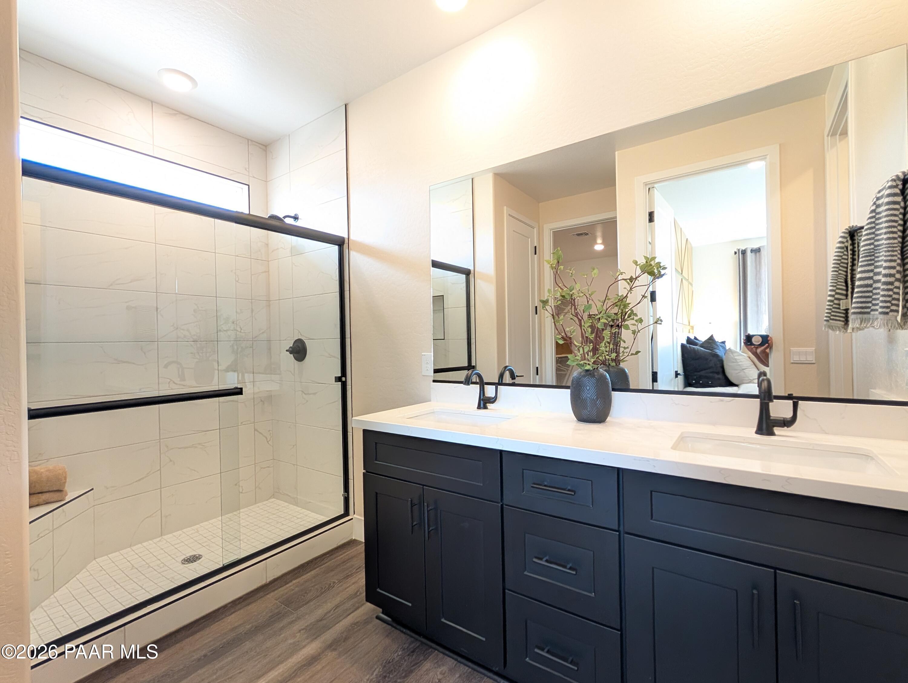 Modern bathroom with dual vanity, black cabinets, and walk-in shower in The Boulder II H at South Ranch, Prescott, Arizona.