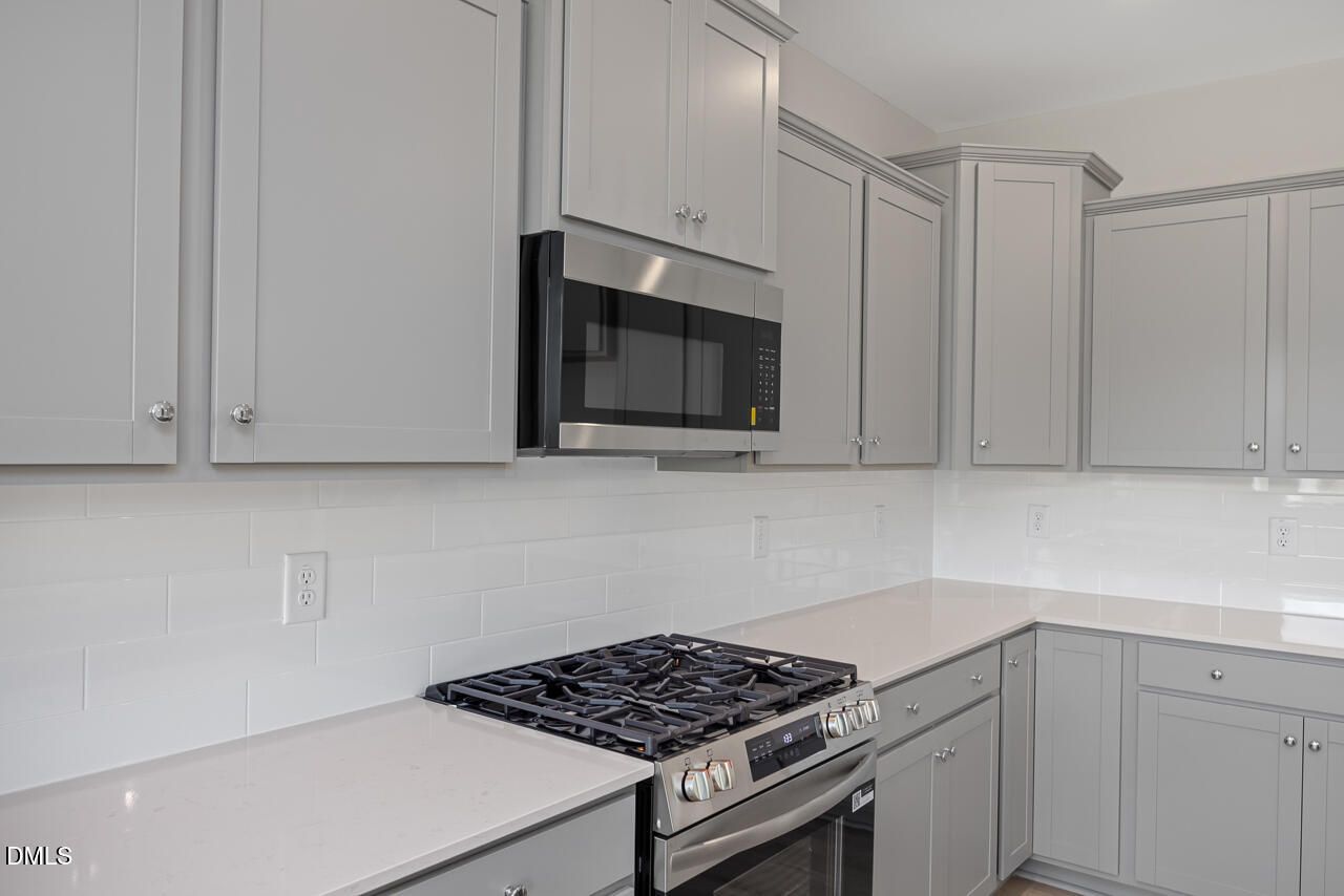 Modern kitchen with gray cabinets, quartz countertops, and stainless steel gas range in The Graham floor plan, Springvale.