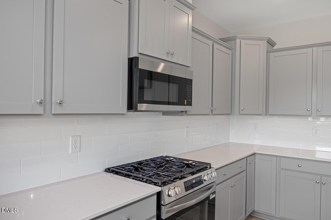 Modern kitchen with gray cabinets, quartz countertops, and stainless steel gas range in The Graham floor plan, Springvale.