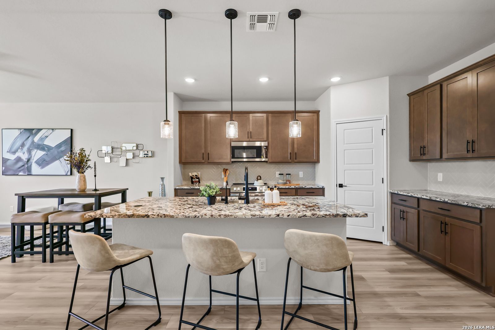 Modern kitchen with granite island, pendant lights, and dark wood cabinets in The Douglas C floor plan, Hannah Heights.