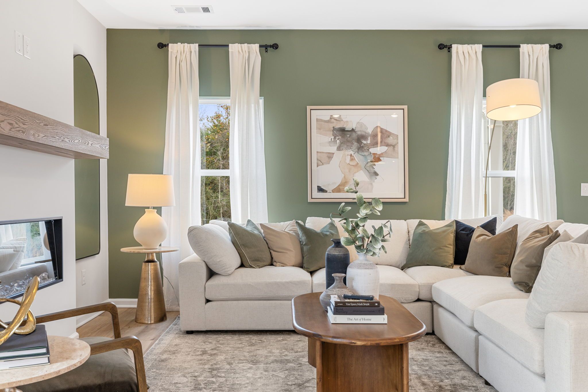 Cozy living room at Cedar Farms in Winder GA with sage green walls, beige sectional sofa, wooden coffee table, and modern fireplace