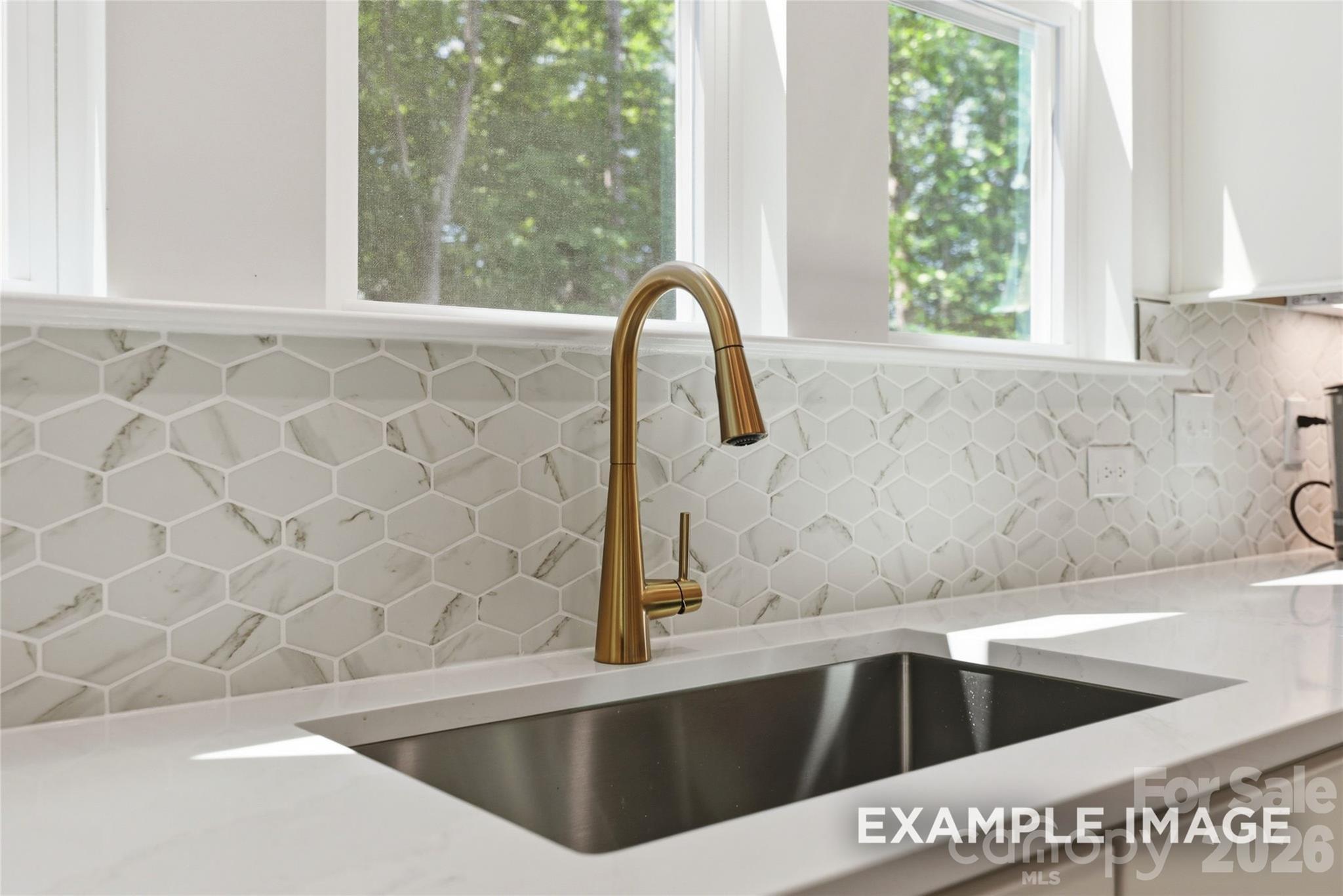 Brass faucet with marble hexagon tile backsplash and quartz countertop at kitchen sink in Davidson Homes Aspen B, Mooresville NC