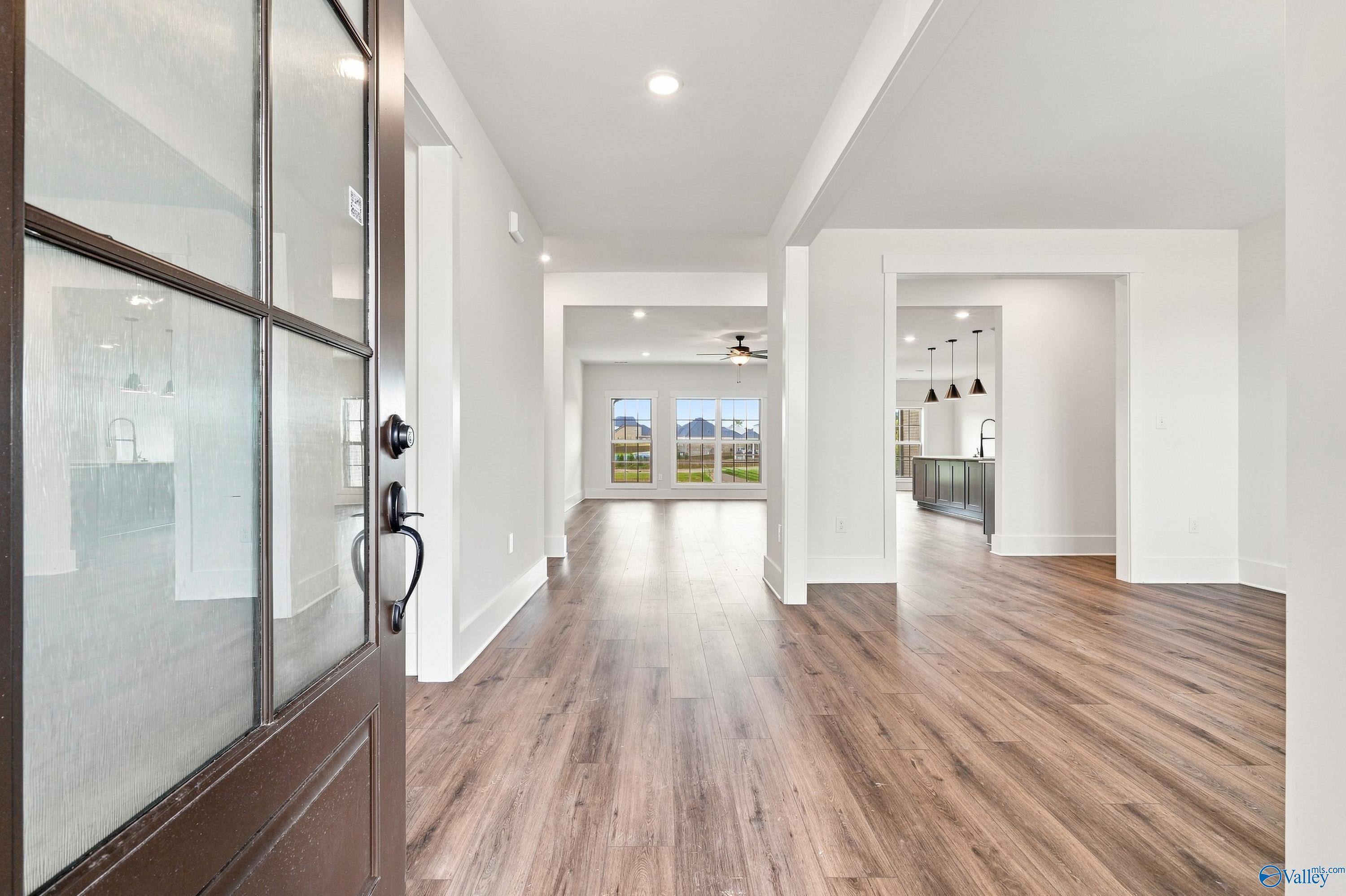 Foyer with glass-panel front door and hardwood-style flooring opening to great room and kitchen in The Valencia by Davidson Homes, Huntsville