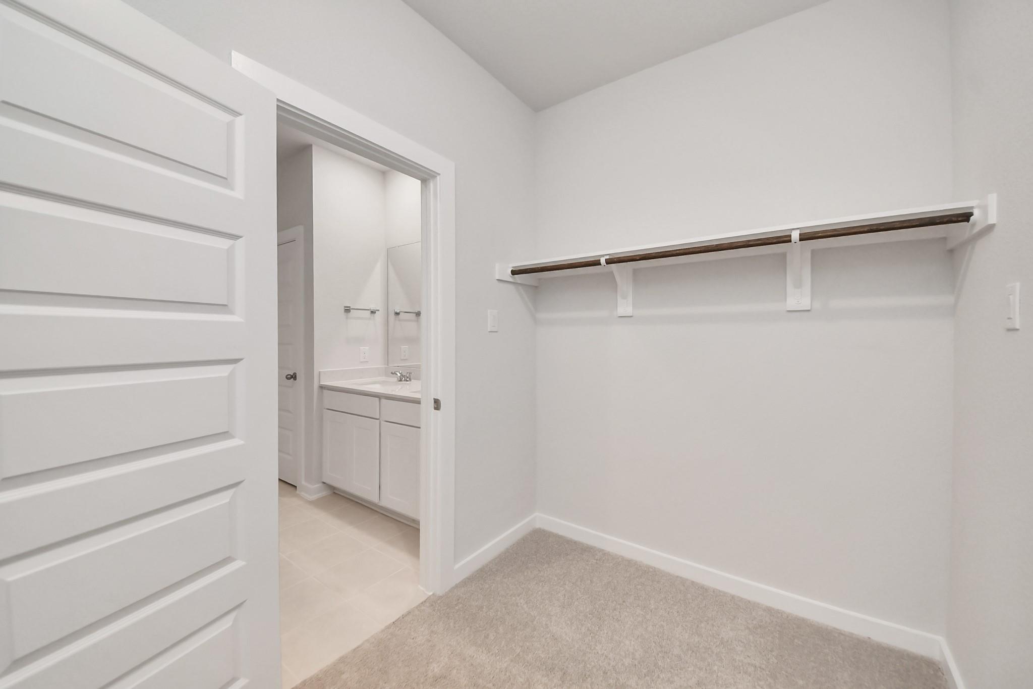 Walk-in closet with carpet and shelving in The Blanco E floor plan at Caney Creek Place, Conroe, Texas.