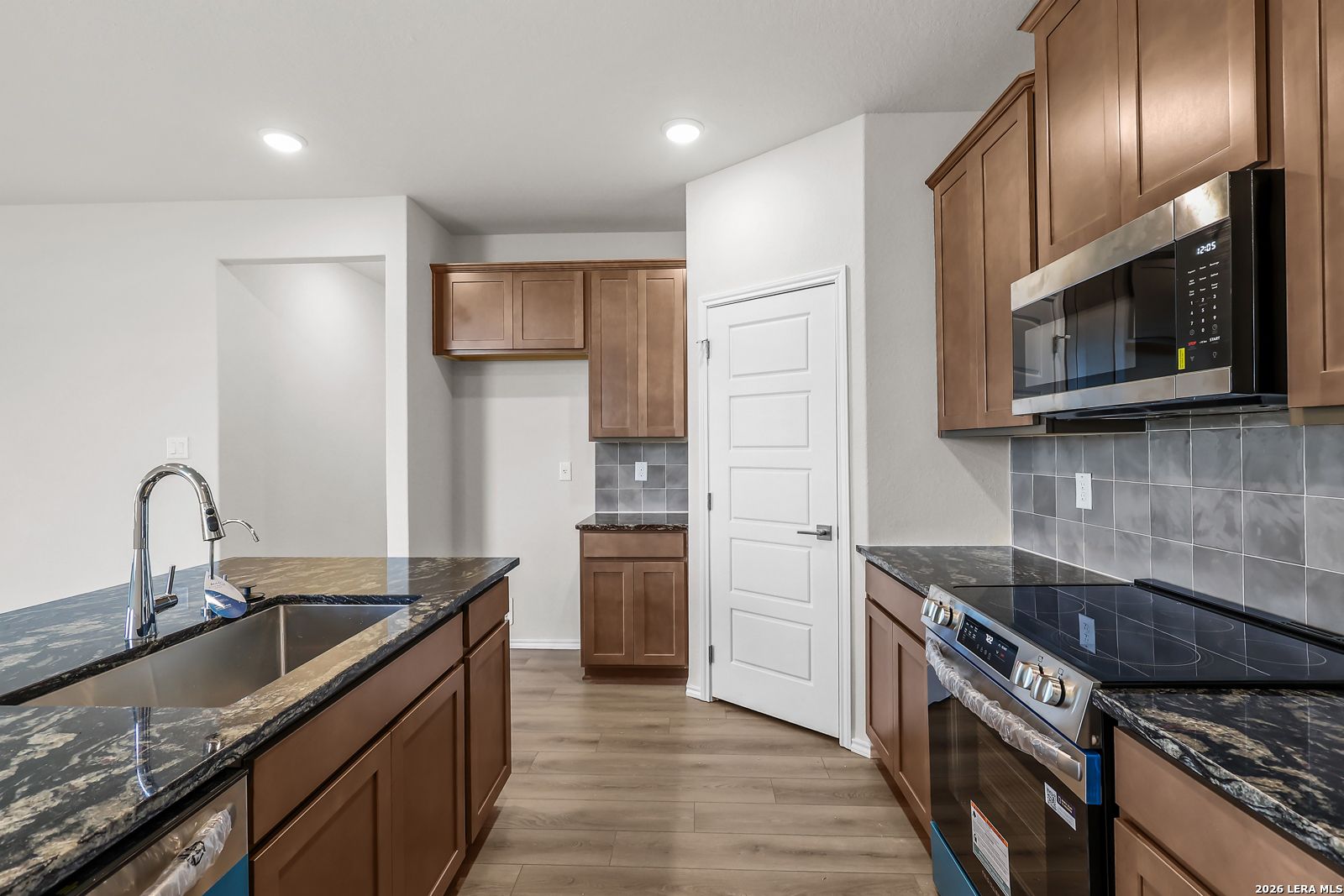 Modern kitchen with dark granite countertops and stainless appliances in The San Marcos F, Davidson Homes, San Antonio.